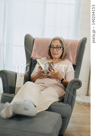 Senior woman reading book sitting relax calm at home quietly in soft sunlight Senior woman reading book sitting relax calm at home quietly in soft sunlight 140204153