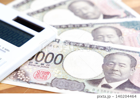 一万円紙幣と電卓 - テーブルの上に置かれた10000円札の紙幣と電卓 140204464
