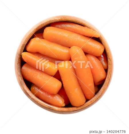 Whole baby carrots, conserved in water, in a wooden bowl. Canned small carrots, Daucus carota, offering a tender, slightly sweet flavor with bright orange color. Isolated, close-up, from above. Photo Whole baby carrots, conserved in water, in a wooden bowl. Canned small carrots, Daucus carota, offering a tender, slightly sweet flavor with bright orange color. Isolated, close-up, from above. Photo 140204776
