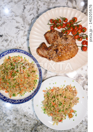 Grilled pork chop, fried rice, cherry tomato, plate, meal, marble counter with savory home dinner overhead view 140205676