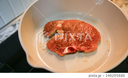 Steak, pan, meat, spice, oil, cooking raw seasoned pork steak frying in kitchen cookware closeup Steak, pan, meat, spice, oil, cooking raw seasoned pork steak frying in kitchen cookware closeup 140205680