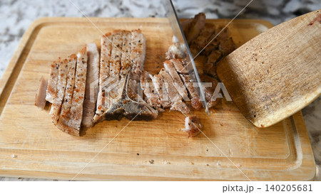 Grilled pork chop, sliced meat, cutting board, knife, kitchen, wooden board with seasoned food preparation Grilled pork chop, sliced meat, cutting board, knife, kitchen, wooden board with seasoned food preparation 140205681