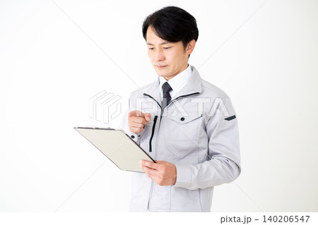書類のバインダーを持つグレーの作業着のミドル男性ビジネスマン白バック 140206547
