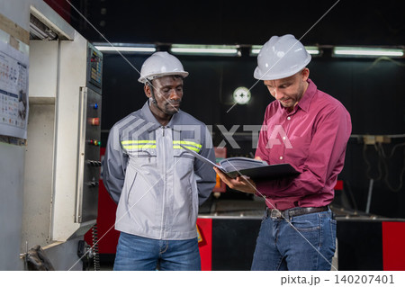 Collaboration between engineers and technicians in industrial setting factory floor documentation review professional environment close-up perspective 140207401