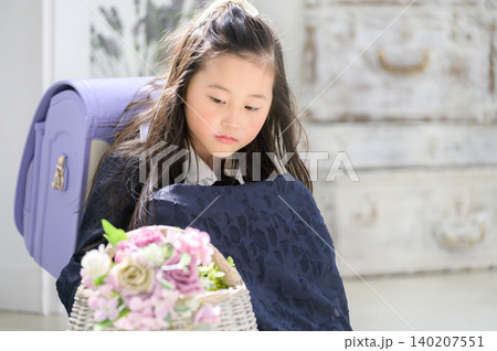 ランドセルを背負って花の入ったカゴを眺める日本人の女の子 140207551