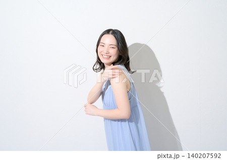 白背景で腕に日焼け止めを塗る日本人女性のビューティイメージ 140207592