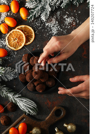 Hands reach for chocolate snacks in a bowl with winter decor Hands reach for chocolate snacks in a bowl with winter decor 140207724