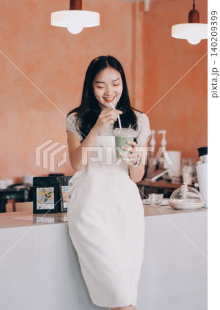 Young woman drinking iced coffee outside a chocolate shop 140209399