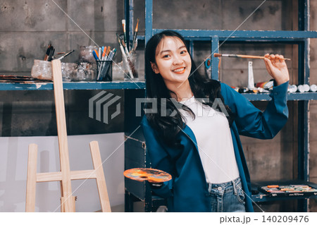 Female artist wears black hat posing near picture indoor the studio Female artist wears black hat posing near picture indoor the studio 140209476