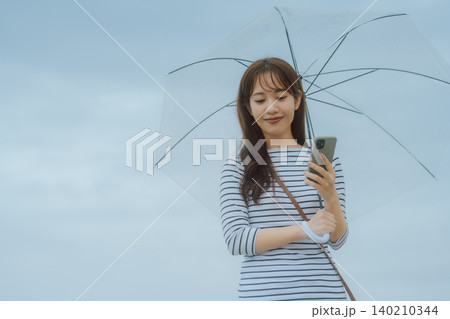 雨の日スマホ操作の女性 雨の日スマホ操作の女性 140210344