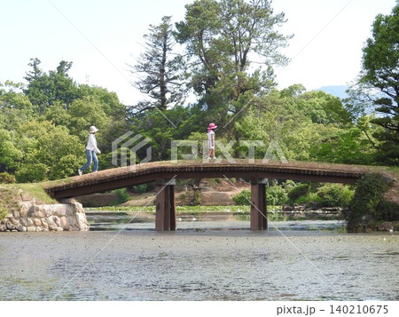 岡山県津山市にある回遊式日本庭園「衆楽園」：土橋を渡る子供連れ 140210675