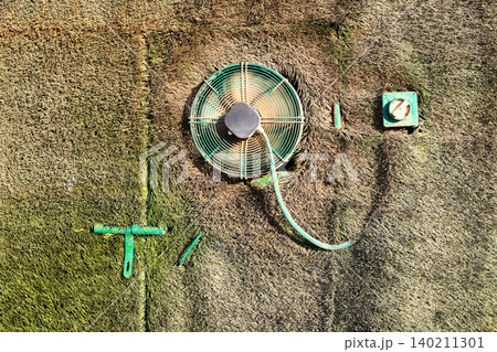 Secret door concealed by grass with a small ventilation fan, hidden in a natural outdoor setting 140211301