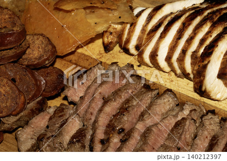 Close up of sliced meat chicken steak choizo platter on a wooden chopping board 140212397