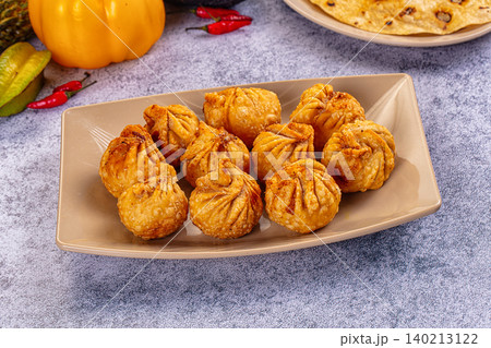 Golden fried momo dumplings on rectangular beige plate with fresh vegetables Golden fried momo dumplings on rectangular beige plate with fresh vegetables 140213122