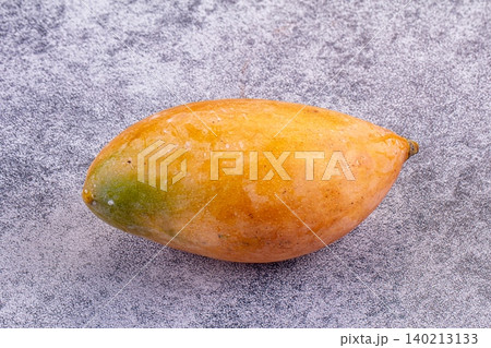 Single ripe mango fruit on textured grey background Single ripe mango fruit on textured grey background 140213133