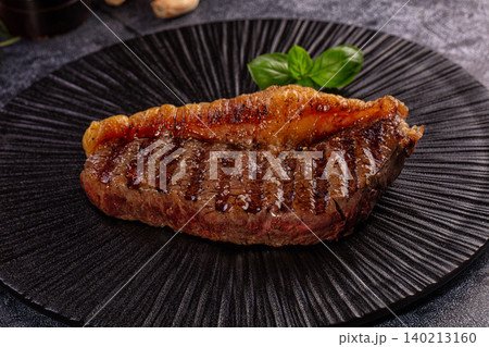 Grilled Beef Steak with Golden Fat Cap and Fresh Basil Leaves on Dark Plate Grilled Beef Steak with Golden Fat Cap and Fresh Basil Leaves on Dark Plate 140213160