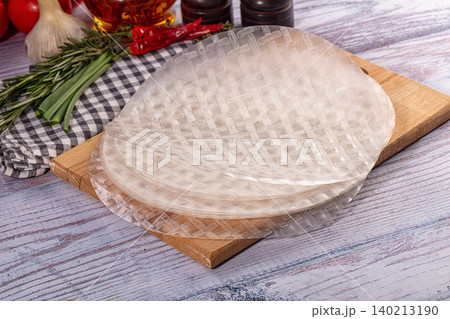 Rice paper wrappers for spring rolls on wooden board with fresh herbs and vegetables Rice paper wrappers for spring rolls on wooden board with fresh herbs and vegetables 140213190