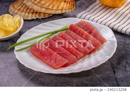 Fresh tuna sashimi slices on white plate with green onion garnish and pickled ginger Fresh tuna sashimi slices on white plate with green onion garnish and pickled ginger 140213206