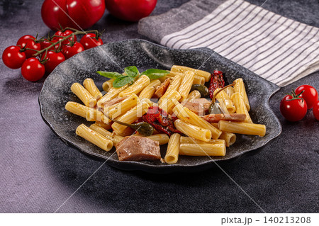 Rigatoni pasta with tuna, sun dried tomatoes, capers, and basil on dark plate Rigatoni pasta with tuna, sun dried tomatoes, capers, and basil on dark plate 140213208