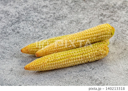 Fresh raw baby corn on textured grey stone background Fresh raw baby corn on textured grey stone background 140213318