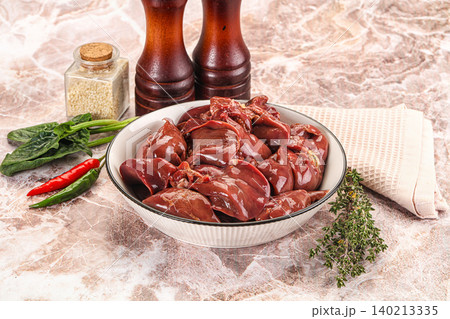 Raw chicken liver in bowl with spices and vegetables on marble table Raw chicken liver in bowl with spices and vegetables on marble table 140213335