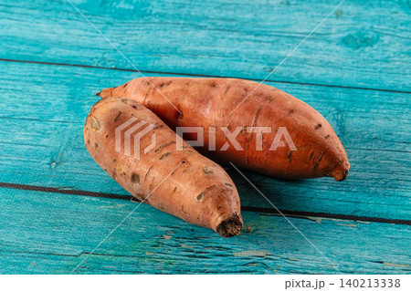 Raw sweet potatoes on blue wooden background 140213338