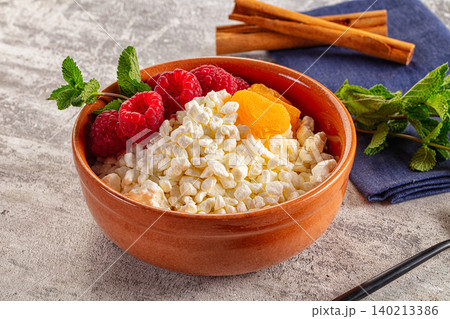 Grain cottage cheese with raspberries and dried apricots in clay bowl Grain cottage cheese with raspberries and dried apricots in clay bowl 140213386
