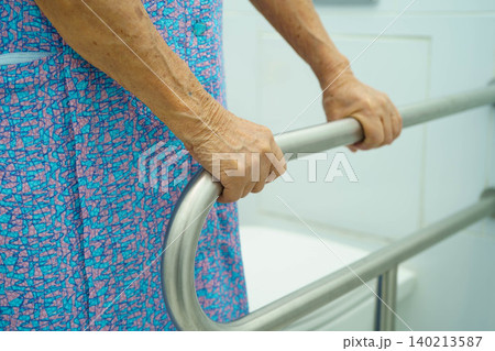Asian elderly woman patient use toilet support rail in bathroom. Asian elderly woman patient use toilet support rail in bathroom. 140213587