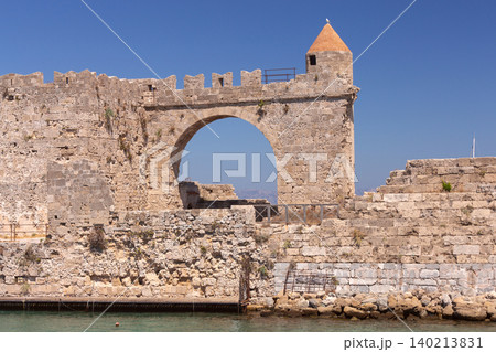 Stone lighthouse tower and medieval harbor walls in Rhodes on sunny clear summer day Stone lighthouse tower and medieval harbor walls in Rhodes on sunny clear summer day 140213831