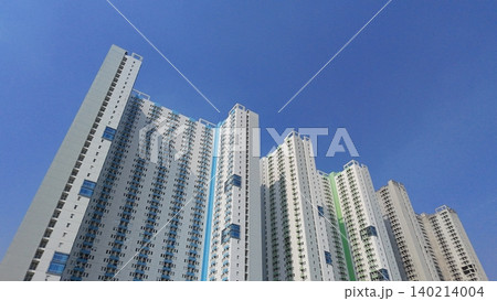 Low-angle view of modern high-rise residential apartment buildings against a blue sky Low-angle view of modern high-rise residential apartment buildings against a blue sky 140214004
