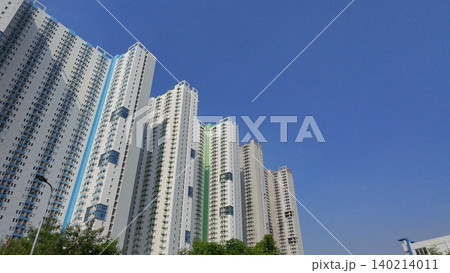 Low-angle view of modern high-rise residential apartment buildings against a blue sky Low-angle view of modern high-rise residential apartment buildings against a blue sky 140214011