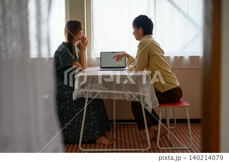 室内でノートPCを囲む二人 140214079