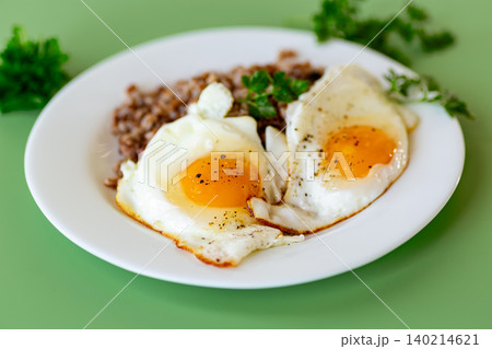 Fried eggs with buckwheat and parsley on white plate Fried eggs with buckwheat and parsley on white plate 140214621