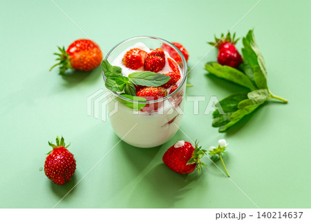Fresh strawberry yogurt dessert with mint on green background Fresh strawberry yogurt dessert with mint on green background 140214637