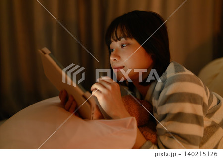 ベッドでタブレットを見る女性 ベッドでタブレットを見る女性 140215126