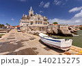 Historic waterfront villa overlooking the harbor with a traditional fishing boat moored beside the quay in Cascais, Portugal. 140215275
