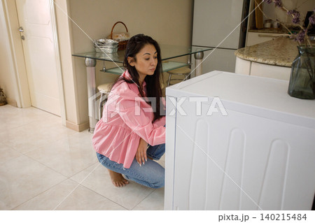 Healthy woman turning on dishwasher at home 140215484
