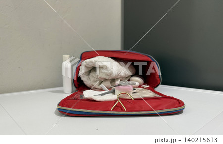 Tools and items in a red bag on a white table with various grooming  140215613