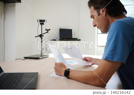 Man focused on work, analyzing charts while working on laptop in co-working office Man focused on work, analyzing charts while working on laptop in co-working office 140216142