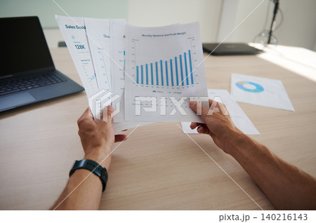 Man  focused on work, analyzing charts while working on laptop in co-working office 140216143