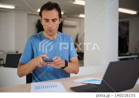 Man  focused on work, analyzing charts while working on laptop in co-working office 140216155
