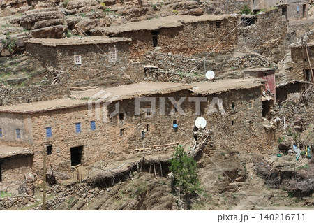 Traditional stone houses wit satellite dishes, and small windows, built into a rugged mountainside in a rural village. Traditional stone houses wit satellite dishes, and small windows, built into a rugged mountainside in a rural village. 140216711