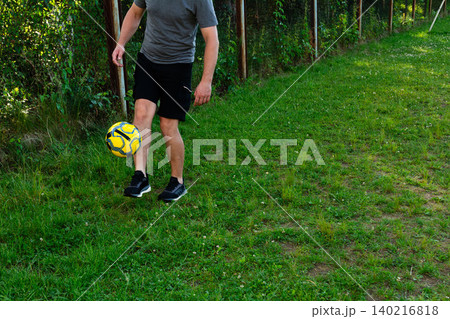 Man juggling soccer ball outdoors near a fence.  Active leisure, healthy lifestyle. 140216818