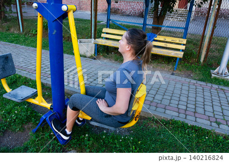Woman exercising on outdoor fitness equipment. Healthy lifestyle and outdoor workout. Woman exercising on outdoor fitness equipment. Healthy lifestyle and outdoor workout. 140216824