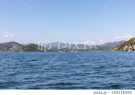 Scenic view across Skadar Lake with mountains and blue sky, Virpazar area Scenic view across Skadar Lake with mountains and blue sky, Virpazar area 140216988