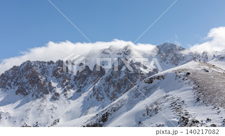 Snowy peaks and rocky ridges in Alay Valley mountain landscape under blue sky Snowy peaks and rocky ridges in Alay Valley mountain landscape under blue sky 140217082