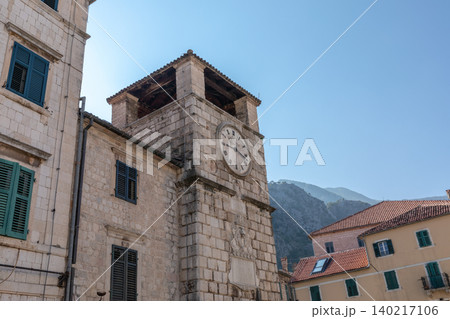 Historic clock tower and stone buildings in Kotor old town, sunny day view Historic clock tower and stone buildings in Kotor old town, sunny day view 140217106