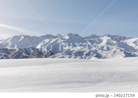 Snowy mountain range and winter steppe landscape in Kyrgyzstan under blue sky Snowy mountain range and winter steppe landscape in Kyrgyzstan under blue sky 140217159