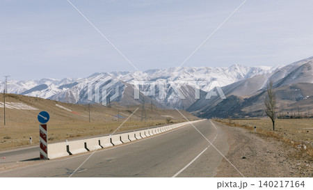 Empty highway leading to snowy Tian Shan mountains in Kyrgyzstan, Central Asia Empty highway leading to snowy Tian Shan mountains in Kyrgyzstan, Central Asia 140217164