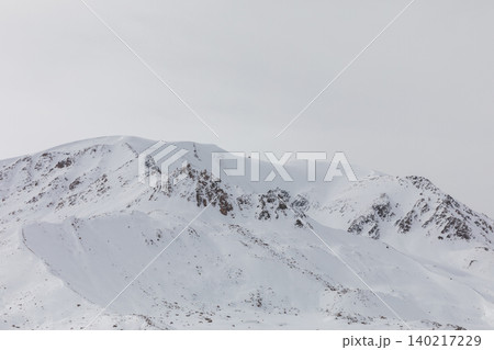 Snowy mountain ridge on Arabel Plateau with rocky peaks under overcast sky Snowy mountain ridge on Arabel Plateau with rocky peaks under overcast sky 140217229